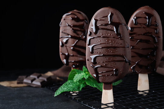 Delicious glazed ice cream bars and mint on black table. Space for text