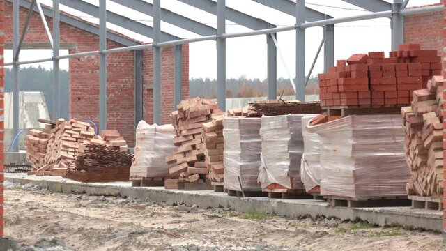 Construction site. Bricks from construction site. Pile of red bricks. pallets and packages of freshly produced red bricks in a construction warehouse on the street.