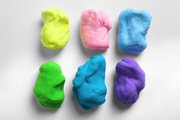 Different color play dough on white background, top view