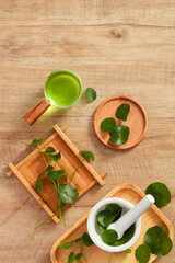 Centella asiatica extract and cosmetic jar template in wooden chopping board and a brown wooden background for centella asiatica advertising , top view , photography plant content