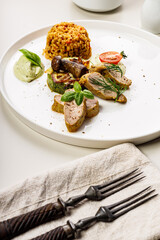 Slices baked turkey fillet with spices. Cooked Turkey meat, zucchini with mushrooms, bulgur garnish. Delicious and healthy food. Table setting on a light background. Vertical shot. Restaurant serving