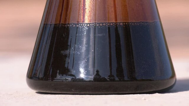 Flask for oxidation of petroleum oils. The flask of oil is at the well of the oil pump. Oil quality control.  Fuel Oil production, a flask with oil on a light background close up
