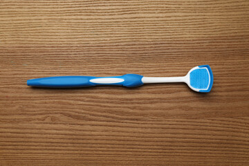 Blue tongue cleaner on wooden table, top view