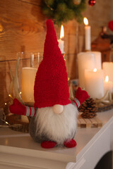 Obraz premium Cute Christmas gnome and festive decorations on mantelpiece in room