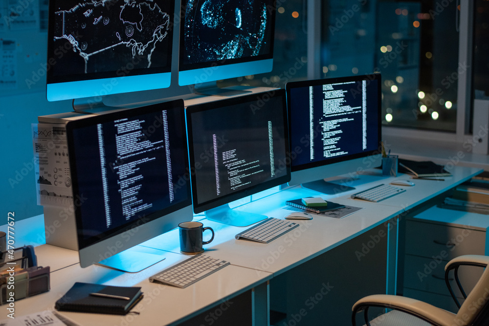 Poster Workplace of contemporary it-engineers with three computers standing on desk in large openspace office
