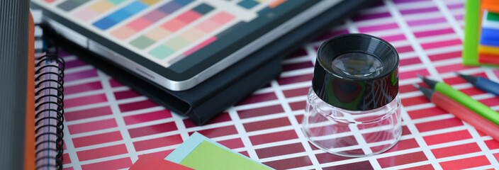 Color palette with colored paper and tablet with color samples lie on table