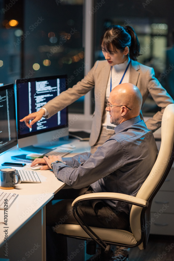 Aufkleber Young Asian businesswoman pointing at data on computer screen during presentation of new project to mature male colleague
