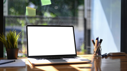Home office desk with laptop computer, notebook and potted plant.