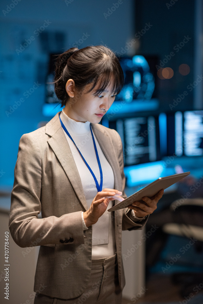 Poster Young Asian businesswoman in formalwear scrolling in tablet while searching in the net for new methods of decoding digital data