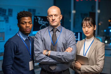 Group of contemporary confident intercultural it-engineers in formalwear standing in front of...