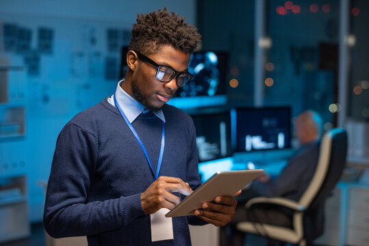 Young African male programmer scrolling in touchpad while looking through new computer software in the internet