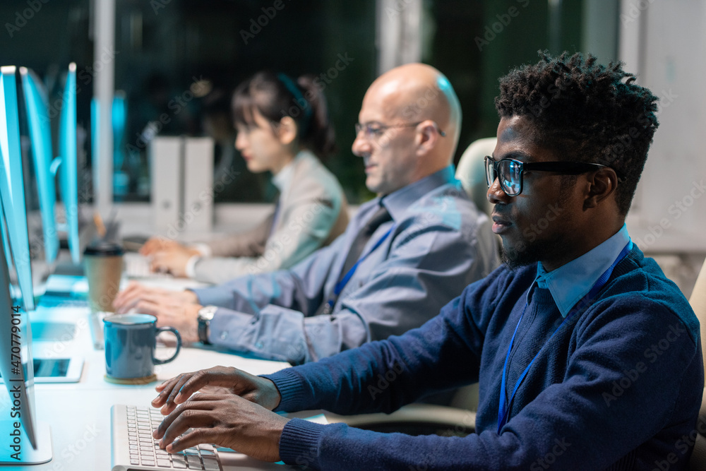 Poster Row of contemporary intercultural programmers working over new software in front of computer monitors in office