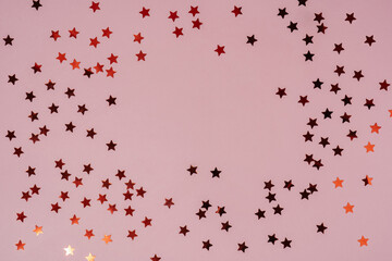 Abstract pink background with sparkles in the shape of stars.