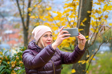 Middle-aged woman taking a photo in a park