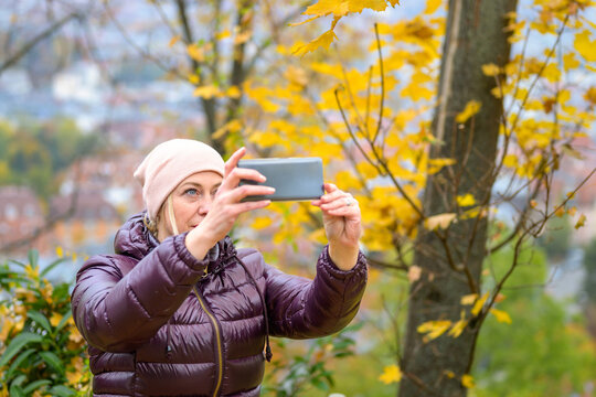 Middle-aged woman taking a photo in a park