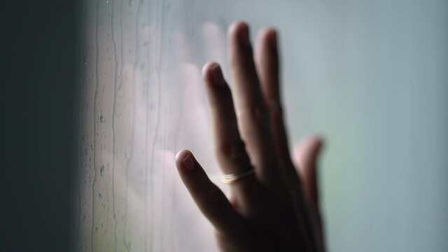 Hand leaning on window during rainy day, moody day concept