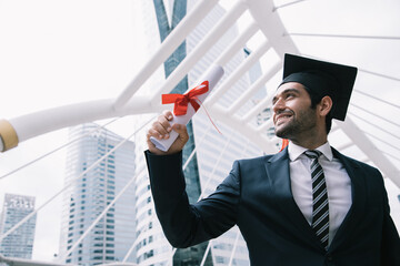Handsome businessman wear graduation degree hat and selfie pictures while sits on stair near cityscape, business education concept - obrazy, fototapety, plakaty