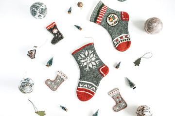 Craft felt Christmas socks and Christmas ornaments, baubles, fir-trees on white background. Cozy aesthetic holiday celebration setting
