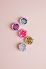 Shiny glitter powder for festive manicure Christmas party on pink background