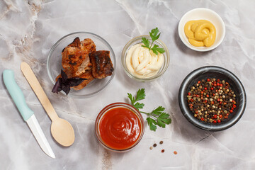 Grilled pork in a bowl with sauces and greens.