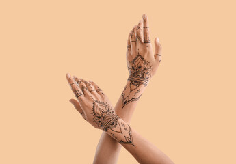 Female hands with henna tattoo on color background