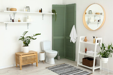 Interior of restroom with toilet bowl and shelves with bathroom accessories