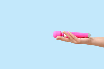 Female hand with vibrator on color background