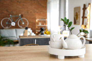 Fototapeta na wymiar Tray with teapot set on studio apartment background