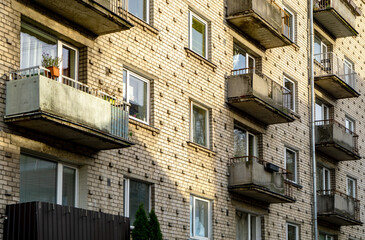 Fototapeta na wymiar Facade texture of an old white brick multi-storey apartment house with balconies. Shine with the sun of the day.