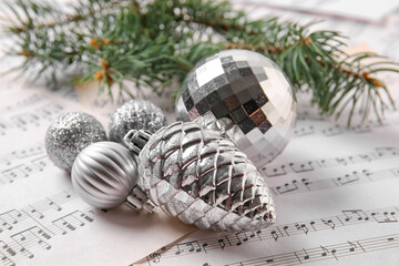 Fir tree branch, Christmas toy pine cone and ball on note sheets, closeup