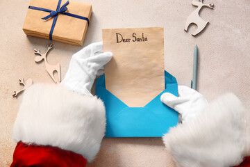 Santa Claus holding wish list letter with text DEAR SANTA on light table