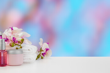 Towels with flowers on light table against blurred background