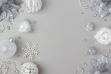 Holiday frame made silver and white shiny christmas decorations on grey background. Happy Christmas, Xmas and New Year concept. Top view, Flat lay, Copy space
