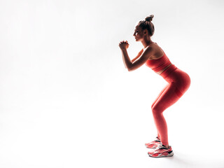 Fitness confident woman in pink sports clothing. Young beautiful model with perfect body. Female isolated on white background in studio. Doing forward squats. Stretching out before training