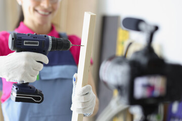 Happy woman construction site worker use drill to make hole in wooden plank