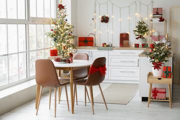Interior of light kitchen with dining table, Christmas trees and glowing lights