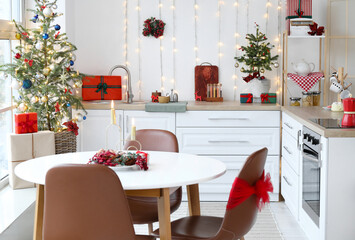 Interior of light kitchen with white counters, Christmas trees and glowing lights