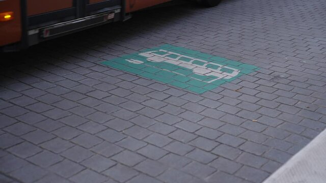 Electric bus leaving the energy station after recharging the battery, passing the charging logo sign on the ground