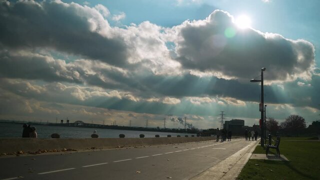 Beautiful god-rays from the sun and clouds on waterfront walkway on a beautiful summer day. Slow motion.