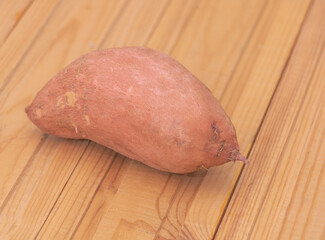 One fresh sweet potato on wooden background - Benefits of sweet potatoes concept