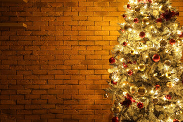 Beautiful Christmas tree with garland near brick wall in dark room