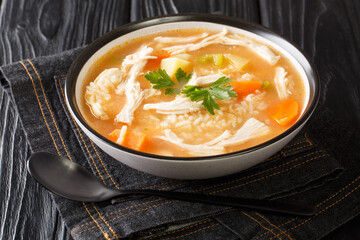 Simple light chicken soup Canja de Galinha with rice, potatoes, celery and carrots close-up in a bowl on the table. horizontal