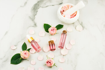 top view of cosmetic and glass bottles with cork lid with rose water and rose essential oil. white background.