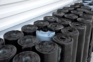 rolls of black asphalt cardboard built side by side. warehouse for roof and home insulators who...