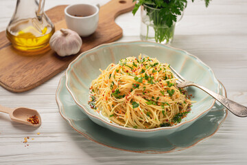 Plate of freshly cooked spaghetti AGLIO E OLIO and ingredients on wooden table