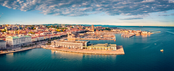 View from flying drone of quay of Trieste city, Italy, Europe. Panoramic morning view of Tourist attraction - Cruise Pier Trieste with Molo Teresiano on background. Traveling concept background. - obrazy, fototapety, plakaty