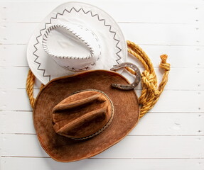 Classic brown and white cowboy hat lasso and horseshoe wild west still life on rough white wooden...