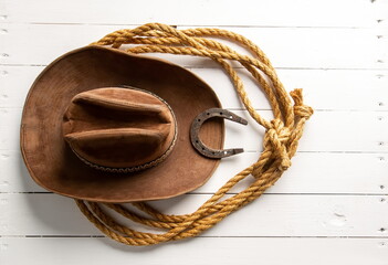 Classic brown cowboy hat lasso and horseshoe wild west still life on rough white wooden table