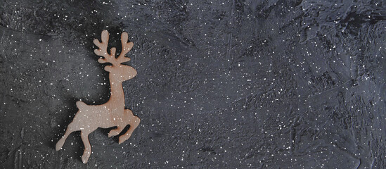 Christmas wooden deer on the grey stone background with a snow