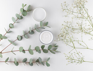white face cream on a white background with eucalyptus and dried flowers